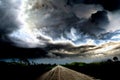 Dark thunder clouds and dramatic storms over a rural road. Royalty Free Stock Photo