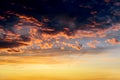 Dark thunderclouds with red orange reflections of the setting sun. Scenic storm clouds lit by the last rays of the sunset. Royalty Free Stock Photo