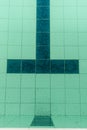 Dark tiles of a pool in the shape of a T that identifies the arrival in a pool