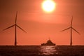 Dark tropical sunrise at sea with ship and wind turbines on the horizon Royalty Free Stock Photo