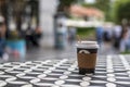 Dark vending coffee in disposable kraft paper cup and plastic lid on table at street cafe Royalty Free Stock Photo