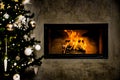 Dark wall with dark Christmas tree with shining fireplace and white christmas decoration