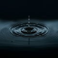 Dark water surface with a single droplet causing ripples. The centered droplet rises in a Royalty Free Stock Photo