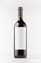 Dark wine bottle with blank white label on white wooden board, mock up, vertical. Royalty Free Stock Photo