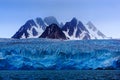 Dark winter mountain with snow, blue glacier ice with sea in the foreground, Svalbard, Norway, Europe