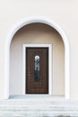 Dark wood front door of a home. View of a rustic front door on a light gray home during the day. Vertical shot. Royalty Free Stock Photo