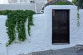 Dark wooden door in white old stone wall with bush. Horizontal photo Royalty Free Stock Photo