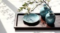 Dark wooden serving tray ceramic turquoise blue vase and jar and antique blue Chinese book with space on white fabric tablecloth