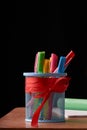 Dark wooden table with pens holder, colorful pens, notebooks and pen. Concept education and back to school