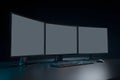 Workspace with three blank computer monitors and a keyboard in a dimly lit room Royalty Free Stock Photo