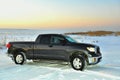 Darkly gray SUV on the snow covered Lake.