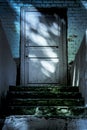 Darkness and horror at the closed entrance door to the ghost house. Dark stone ruined old staircase from the basement with Royalty Free Stock Photo