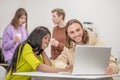 Darkskinned girl and caucasian guy interestedly looking at laptop