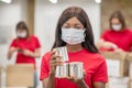 Darkskinned girl in protective mask with canned food