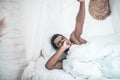 Darkskinned yawning man lying in white bed