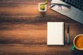 Darkwood office desk table with blank notebook and laptop computer with pen, cup of coffee and supplies. Top view with copy space Royalty Free Stock Photo