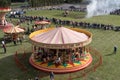 Fun fair carousel with horses in a field with people Royalty Free Stock Photo