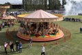 Fun fair carousel with horses in a field with people Royalty Free Stock Photo