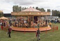 Fun fair carousel with horses in a field with people Royalty Free Stock Photo