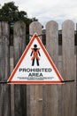 No entry prohibited area sign with cross and man symbol on fence