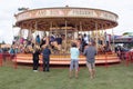 People watching fun fair carousel ride in field Royalty Free Stock Photo