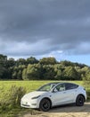 Darlowo, Poland 2023 - elegant modern white Tesla car parked in front of a meadow and park