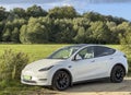 Darlowo, Poland 2023 - elegant modern white Tesla car parked in front of a meadow and park