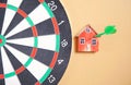 Dart arrow, dartboard and house model on yellow background Royalty Free Stock Photo