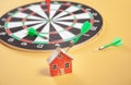 Dart arrow, dartboard and house model on yellow background Royalty Free Stock Photo