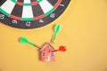 Dart arrow, dartboard and house model on yellow background Royalty Free Stock Photo