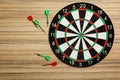 Dart board with color arrows on wooden background, top view. Space for Royalty Free Stock Photo