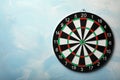 Dart board hanging on light blue wall. Royalty Free Stock Photo