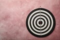 Dart board hanging on pink textured wall Royalty Free Stock Photo