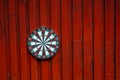 Dart board hanging on a red wooden wall.. Royalty Free Stock Photo