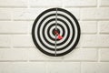 Dart Board on the white wall background. Red dart arrow hitting in the center of dartboard Royalty Free Stock Photo