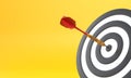 Dart hitting a target on the center on yellow background with copy space Royalty Free Stock Photo