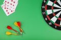 Dartboard, darts and playing cards on a green background flat lay Royalty Free Stock Photo