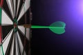 Dartboard with green dart stuck in the center with bright blue light Royalty Free Stock Photo