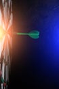Dartboard with green dart stuck in the center with bright blue light Royalty Free Stock Photo