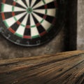 Dartboard with grey wall background. Wooden table with empty space. Darts playing time. Royalty Free Stock Photo