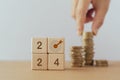 2024 ,dartboard instead of 0 on wood cube block with blurred hand arranging stack of coins. For business target, goal,