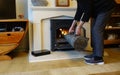 Lady putting coal from a container onto a coal fire in a stove in a dwelling house