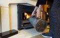 Lady putting coal from a container onto a coal fire in a stove in a dwelling house