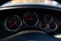 The dashboard of the car with red arrows and carbom trim, a speedometer, tachometer and other tools to monitor the condition of