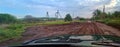 Rural dirt damaged wet road with car tire traces after heavy rain Royalty Free Stock Photo