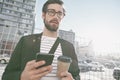 Dashing downtown style. A stylish young man holding his cellphone and a takeaway coffee in the city. Royalty Free Stock Photo