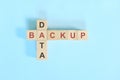 Data backup concept in computer and information technology. Wooden blocks crossword puzzle flat lay in blue background. Royalty Free Stock Photo