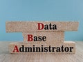 Data Base Administrator symbol. DBA acronym on brick blocks with letters. Beautiful blue background, wooden table. Data Base