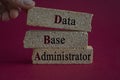 Data Base Administrator symbol. DBA acronym on brick blocks with letters. Beautiful red background. Businessman hand Data Base