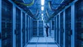 Data center engineer working with laptop in server room with rows of computer racks Royalty Free Stock Photo